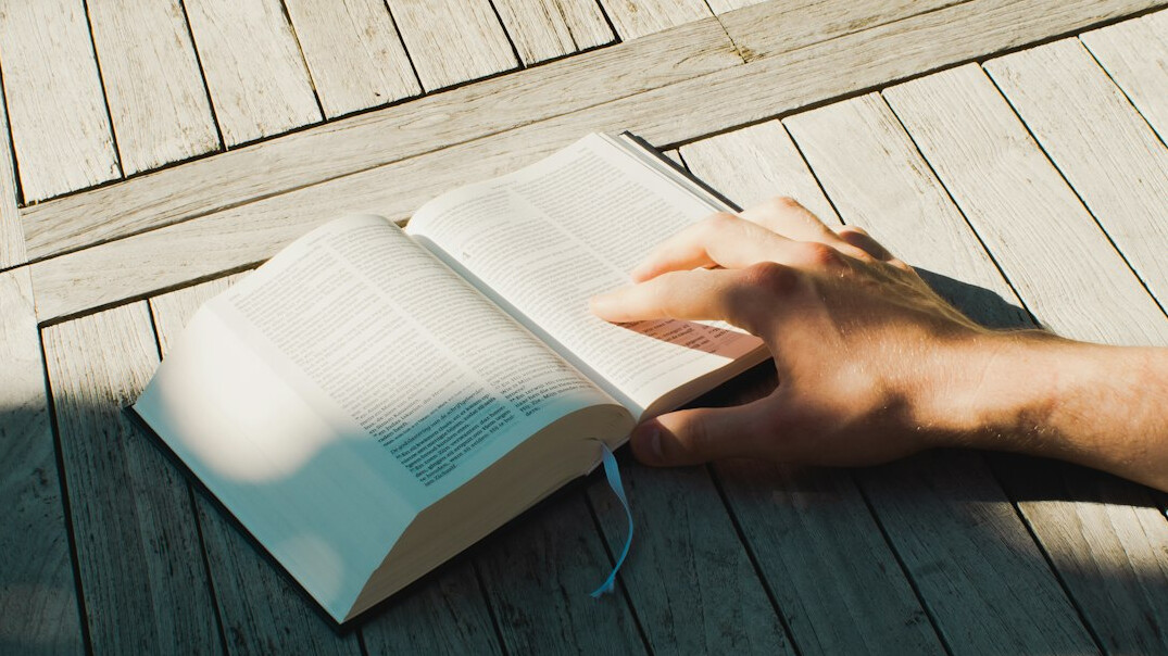 Hand writing in a notebook on a wooden table